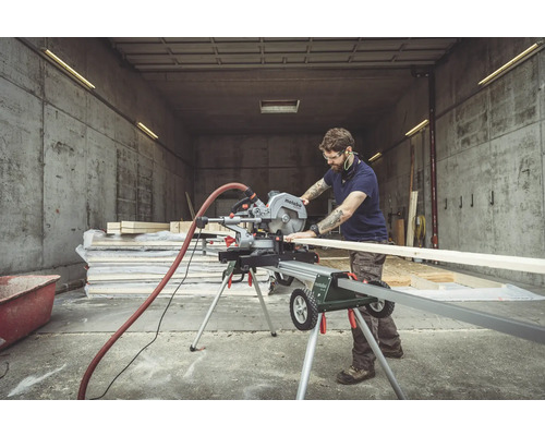 Un homme coupe du bois avec une scie à onglet Metabo dans un atelier.