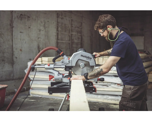 Un homme scie une planche de bois avec une scie à onglet Metabo dans un atelier.
