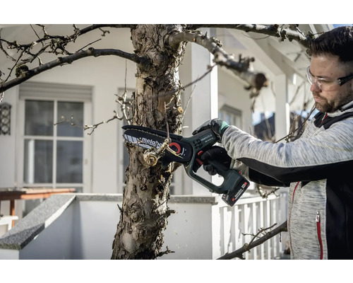 Homme coupant un arbre avec une tronçonneuse à batterie Metabo