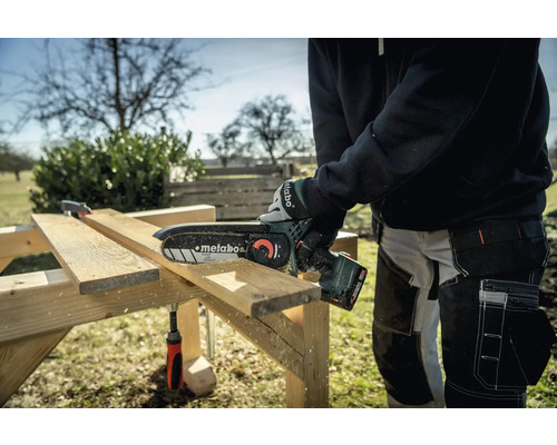 Personne coupant du bois avec une tronçonneuse à batterie Metabo