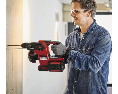 Un homme perce un trou dans un mur avec un marteau perforateur sans fil Einhell Herocco.