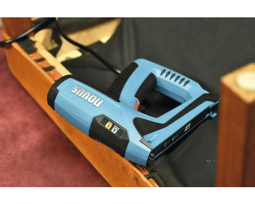 Elektrischer Tacker der Marke Novus auf einem Möbelstück