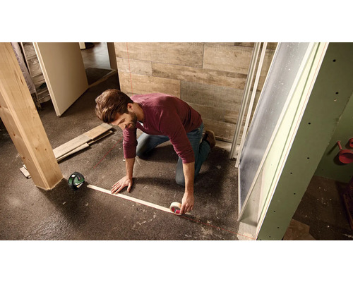 Artisan utilisant un télémètre laser pour mesurer pendant des travaux de rénovation