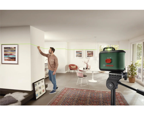 Scène d''intérieur avec un homme marquant une ligne sur un mur à l''aide d''un niveau laser, Logo Bosch