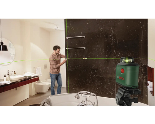 Ein Mann verwendet einen Linienlaser in einem Badezimmer zur Ausrichtung von Handtuchhaltern.