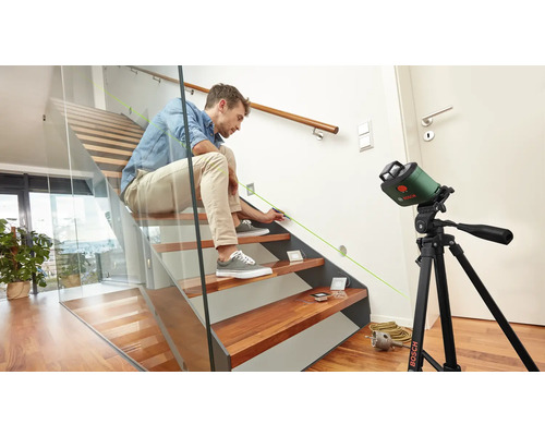 Ein Mann benutzt einen Linienlaser auf einer Treppe für Markierungen.