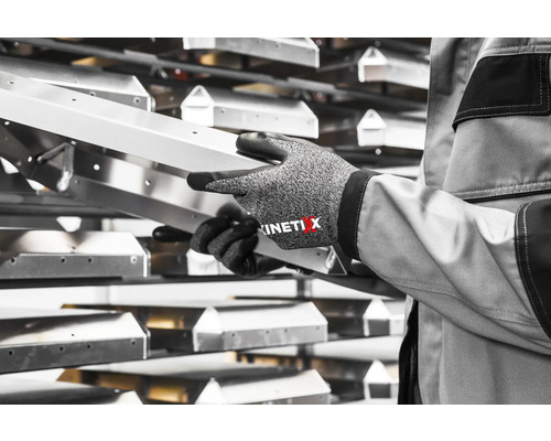 Une personne tient un rail métallique argenté avec des gants de travail