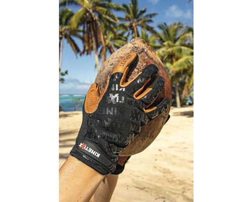 Main avec gants de travail KINETIXX tenant une noix de coco sur la plage