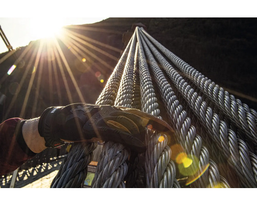 Main gantée touchant des câbles en acier