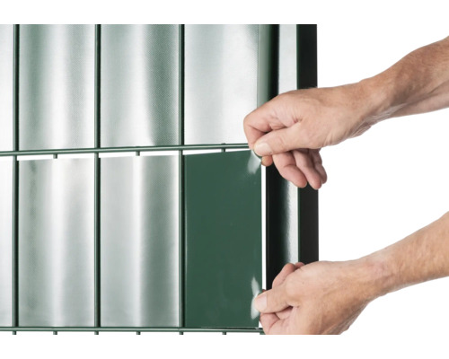 Vue détaillée d''une clôture avec des bandes de protection visuelle et une personne appliquant une bande