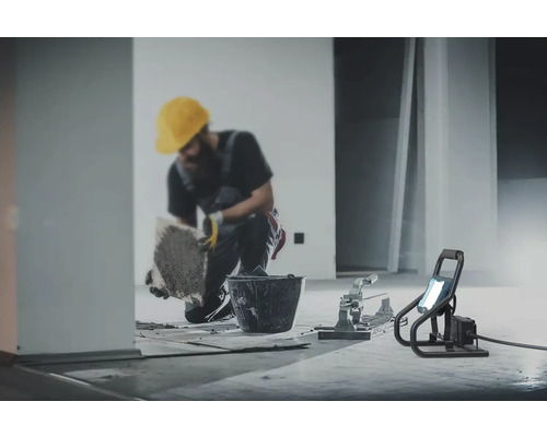 Carreleur au travail avec coupe-carreaux et projecteur de chantier