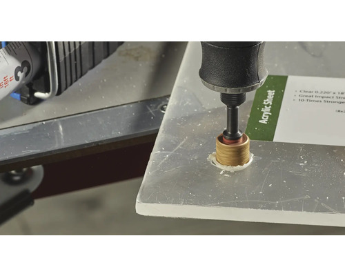 Une perceuse perce un trou dans une plaque acrylique.