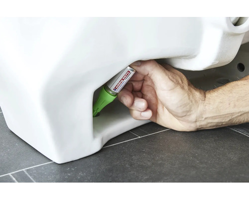 Hand dichtet Toilette mit Dichtstoff ab