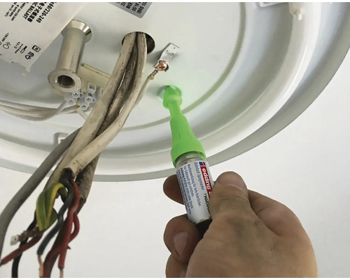 Ein Mann repariert eine Deckenleuchte mit einem Lackstift.