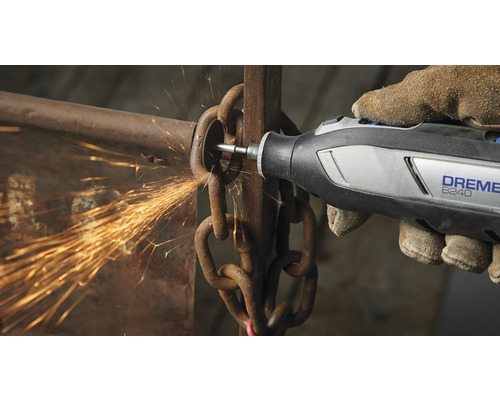 Une personne utilise un outil multifonction Dremel 8240 pour couper une chaîne, ce qui produit des étincelles.