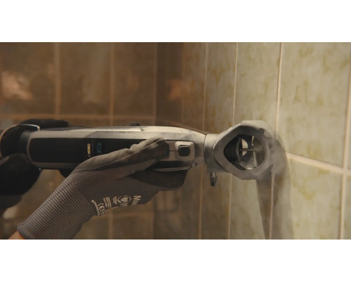 Une personne utilise un outil électrique oscillant sur un mur carrelé.