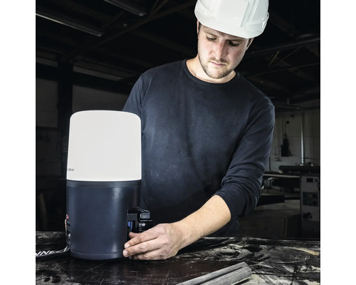 Un homme portant un casque de sécurité installe une lampe de chantier à LED.