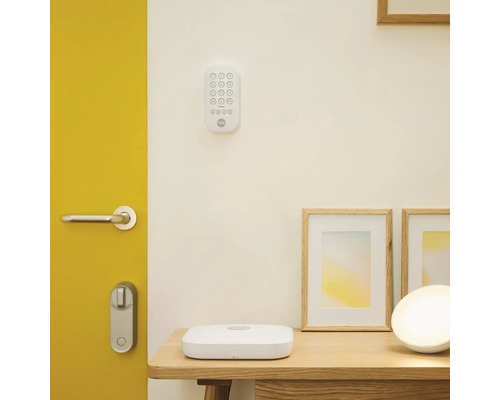 Scène avec serrure de porte numérique, clavier, station de base et cadres photo sur une table