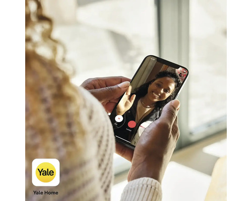 Une personne tient un smartphone avec l''application Yale Home et effectue un appel vidéo.
