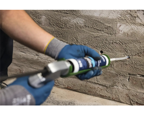 Artisan comblant un trou dans un mur avec du mastic