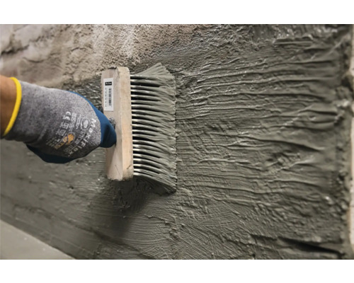 Application de colle à l''aide d''un peigne à colle sur un mur