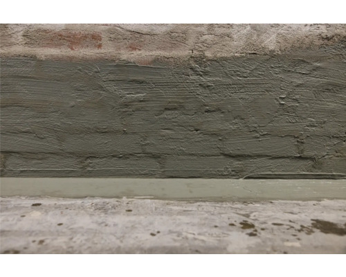 Gros plan d''un mur de briques plâtré et d''un sol en ciment.