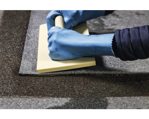 Verarbeiter mit Gummihandschuhen und Fugengummi auf Pflastersteinen