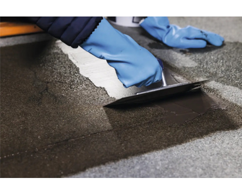 Auftragen von Bitumen Dichtmasse mit einer Glättkelle auf eine Dachfläche