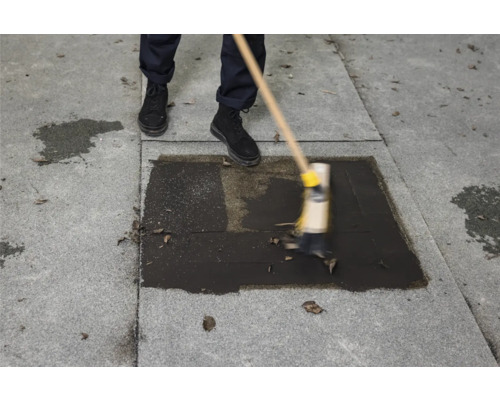 Eine Person reinigt eine Dachfläche mit einem Besen.