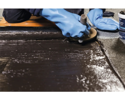 Application de colle bitumineuse à l''aide d''une brosse sur une surface