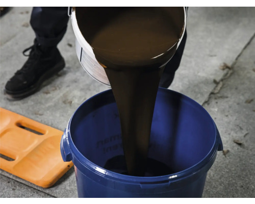 Un produit d''étanchéité liquide est versé dans un seau bleu
