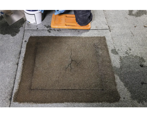 Réparation de toit avec un produit de réparation sur un toit plat.