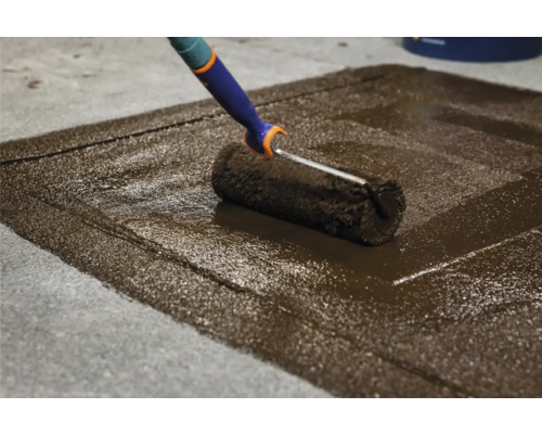 Rouleau de peinture appliquant de la peinture pour sol sur du béton