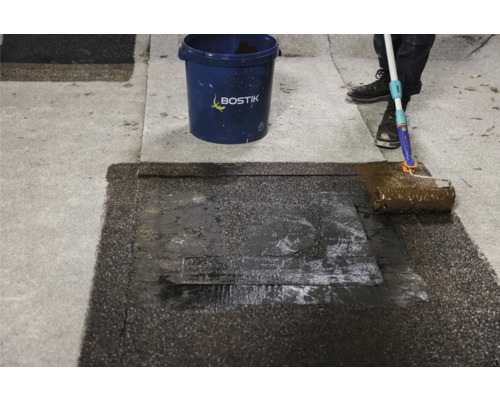 Application d''étanchéité de toiture avec un rouleau à peinture à côté d''un seau et Logo Bostik.