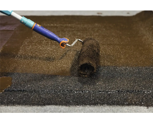 Un revêtement de toit est appliqué à l''aide d''un rouleau à peinture.