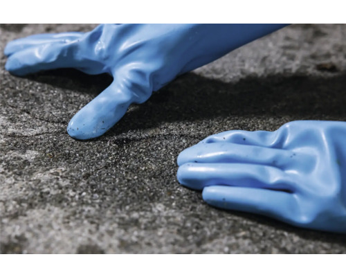 Zwei blaue Schutzhandschuhe liegen auf einer rauen Oberfläche.