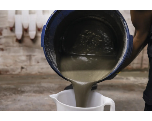 Fliessestrich wird aus einem Eimer in einen Messbecher gegossen.