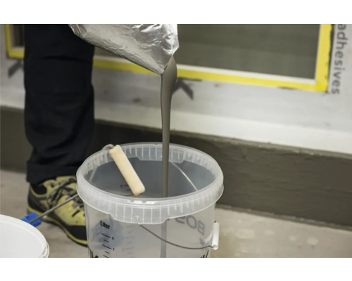 Fliessspachtel wird in einen Eimer gegossen.