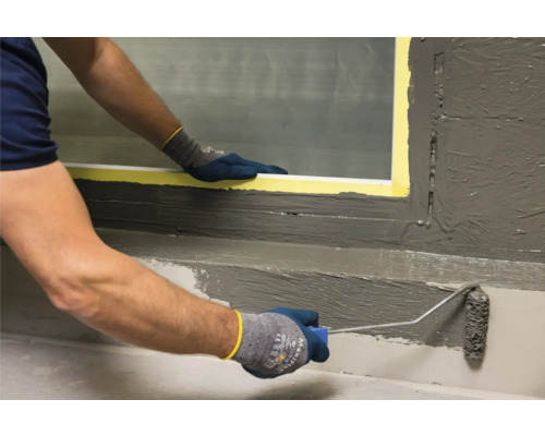 Une personne applique un produit d''étanchéité sur un mur au rouleau.