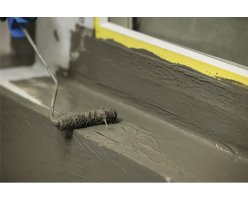 Application de mortier d''étanchéité au rouleau sur un rebord de fenêtre.