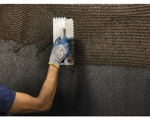 Une personne applique de la colle sur une surface à l''aide d''une spatule