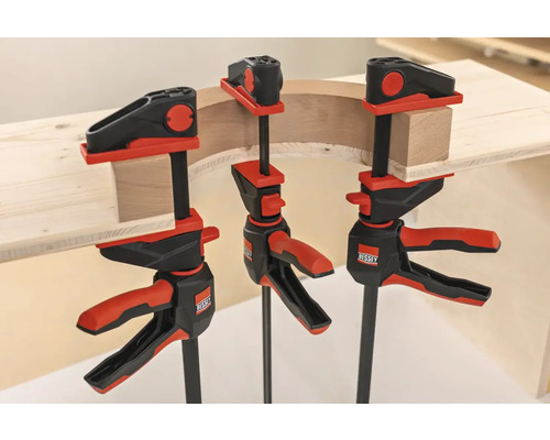 Drei Einhandzwingen von Bessey fixieren ein Werkstück aus Holz.