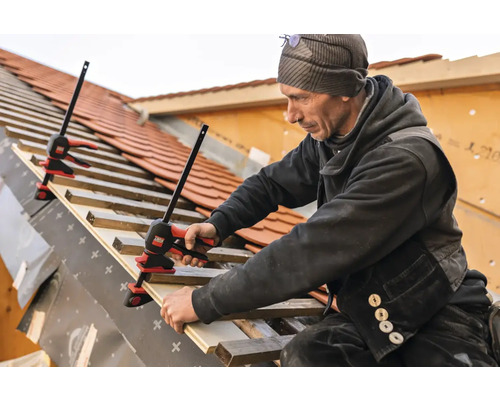 Ein Handwerker befestigt Dachlatten mit Einhandzwingen auf einem Dach.