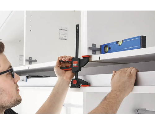 Handwerker befestigt Schrank mit einer Einhandzwinge.