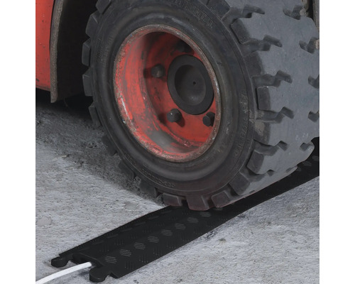 Gabelstaplerreifen fährt über einen Kabelschutz