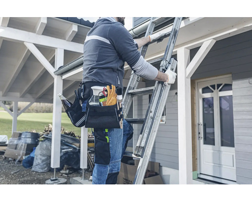 Handwerker auf einer Leiter mit Werkzeugtasche bei der Arbeit im Aussenbereich.