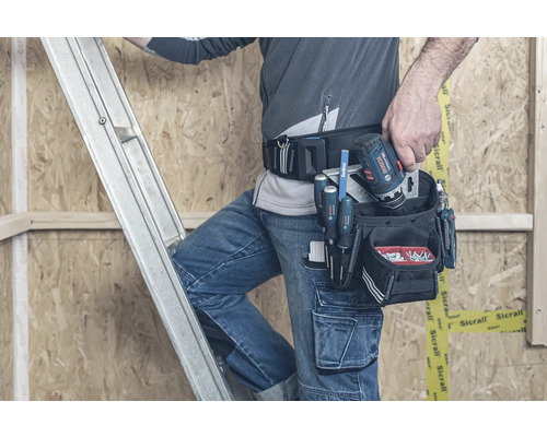 Handwerker auf einer Leiter mit Werkzeug und Akkuschrauber im Werkzeuggürtel