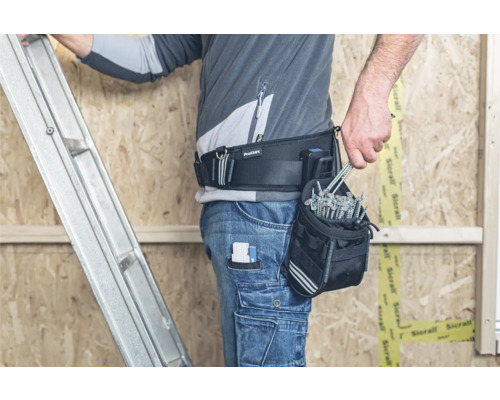 Handwerker mit Werkzeuggürtel und Schrauben vor einer Holzkonstruktion mit Leiter