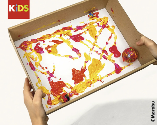 Un enfant tient une boîte avec de la peinture et des billes pour un projet de peinture.