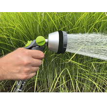 Tête de pulvérisation de tuyau d'arrosage en cours d'utilisation devant de l'herbe verte